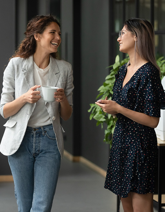 deux femmes souriant et parlant dans un bureau