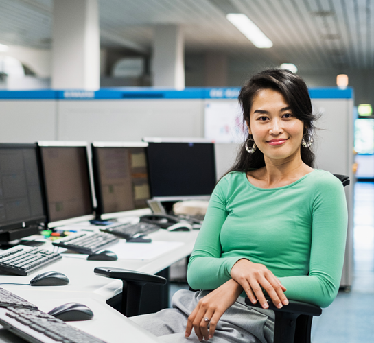 woman smiling in front of several computer screens