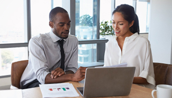 two people in a meeting, working on a computer