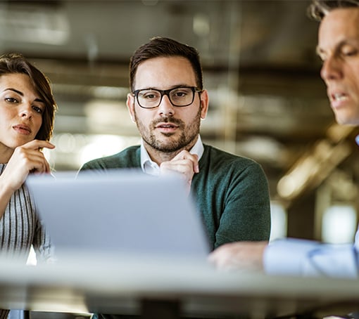 three coworkers in a meeting, looking at a laptop