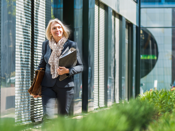 woman walking next to a building with plants