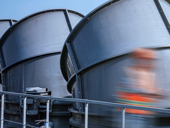 Worker with an orange jacket walking on industrial building roof