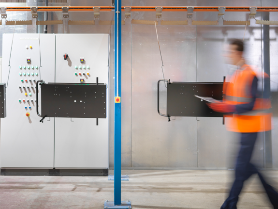 men walking in maintenance room in cement, with an orange jacket 