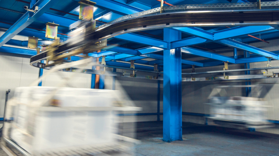 Boxes holding by cables move in a production line factory