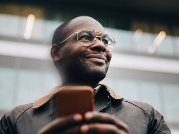 smiling businessman using phone looking away