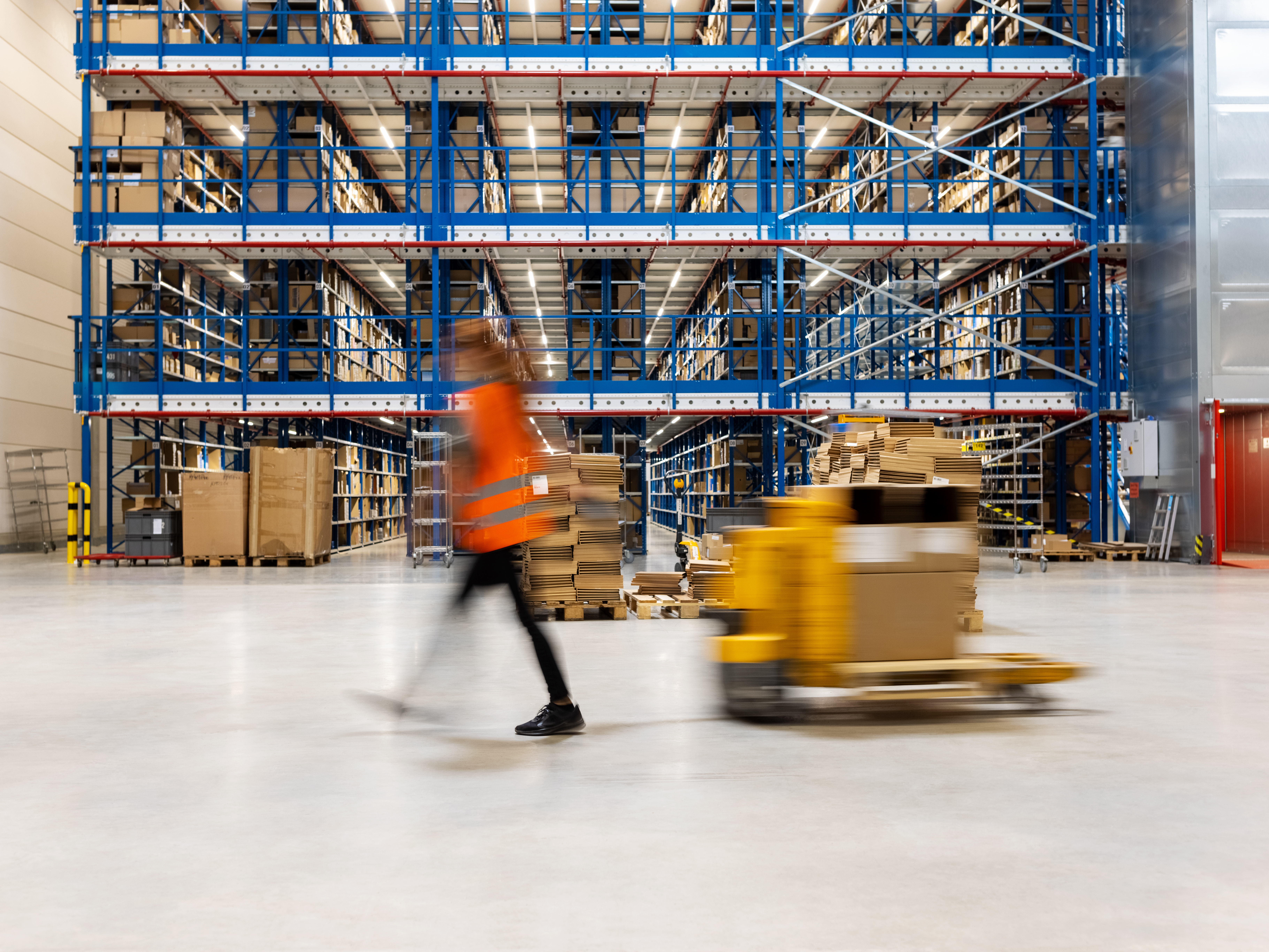 woman pulling on manual forklift in warehouse facility