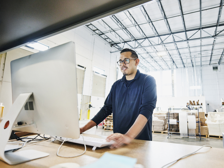 male warehouse worker checking orders at computer workstation